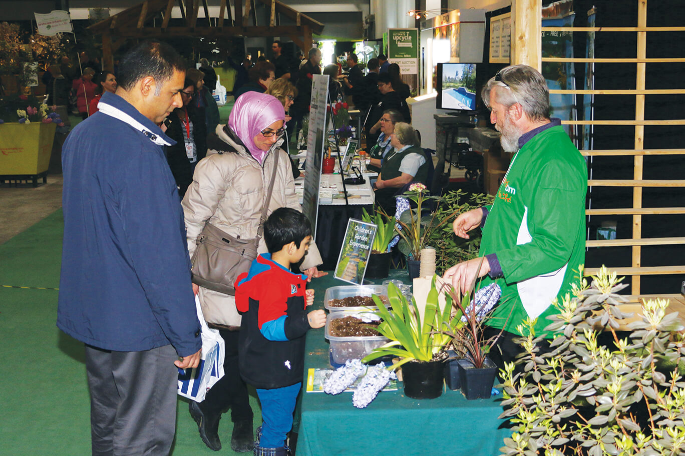 family planting a seed at a vendor table at the home show