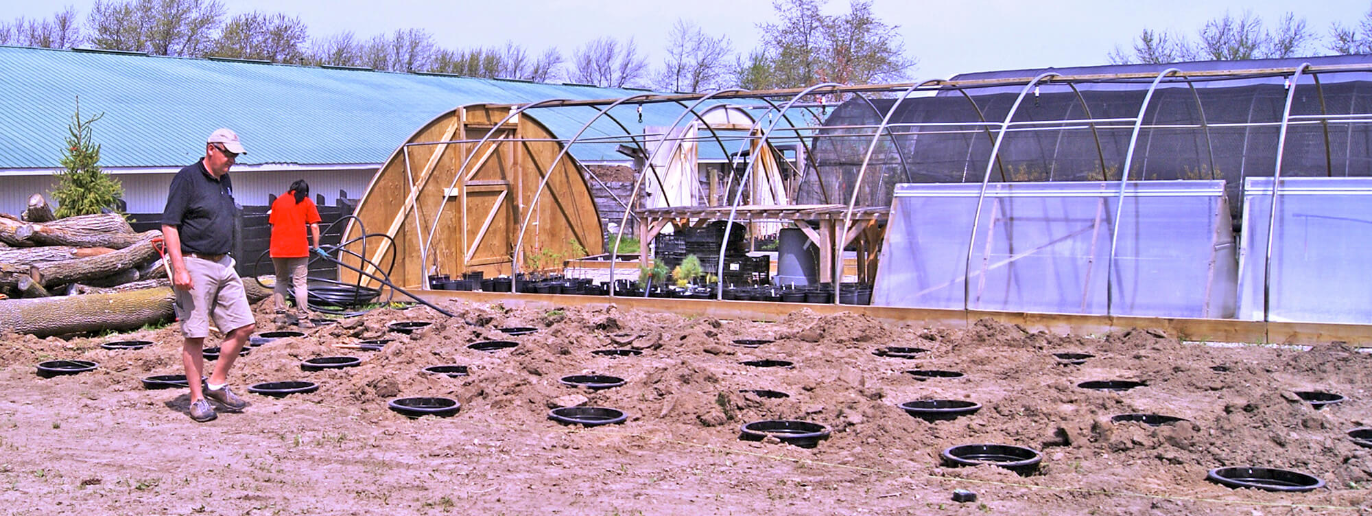 hoop house with pots in the ground beside it