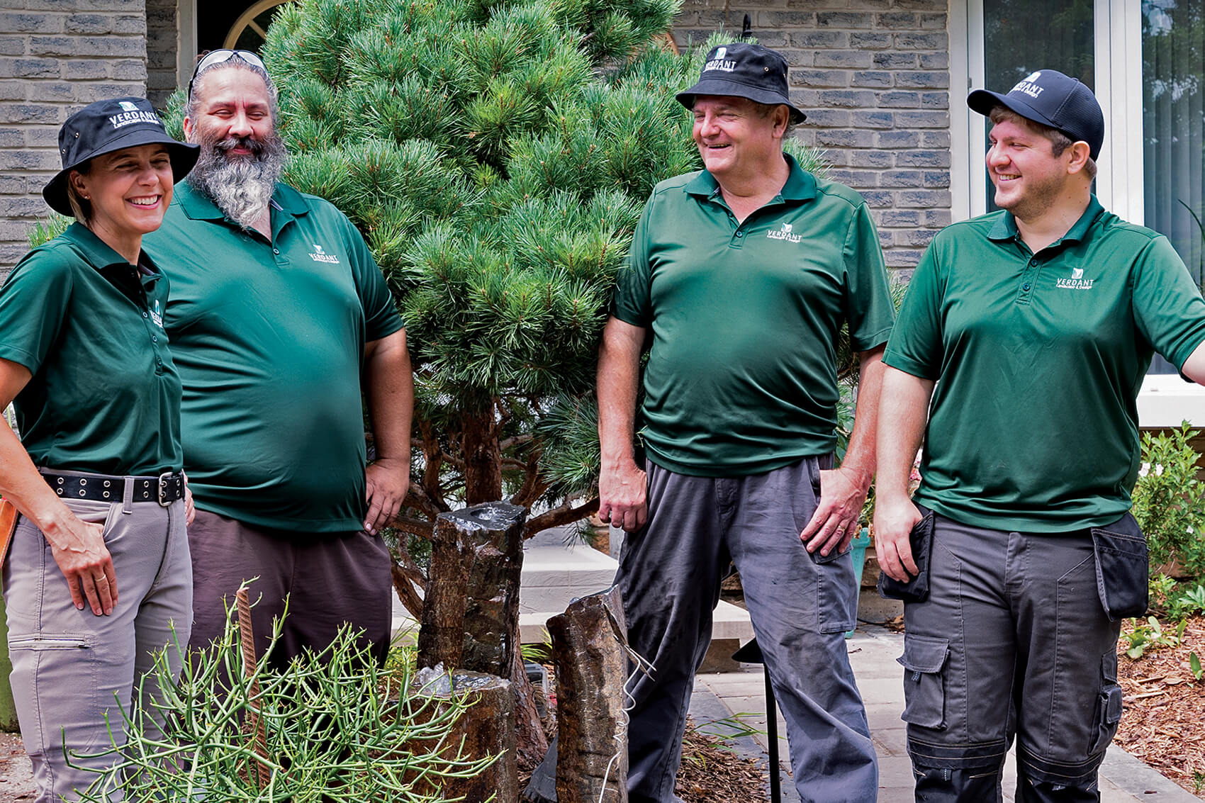 Four landscapers talking outside a home
